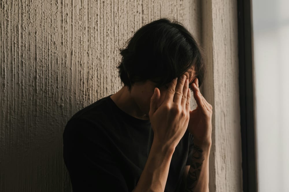 在效率至上的壓力下，一個男人感到工作倦怠，將頭埋在手裡反思。